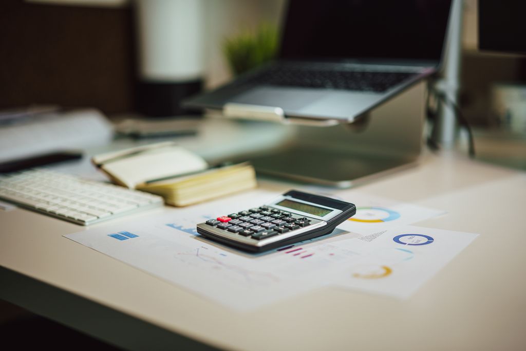 A modern workspace with a laptop, calculator, and documents on a desk, perfect for finance tasks.
