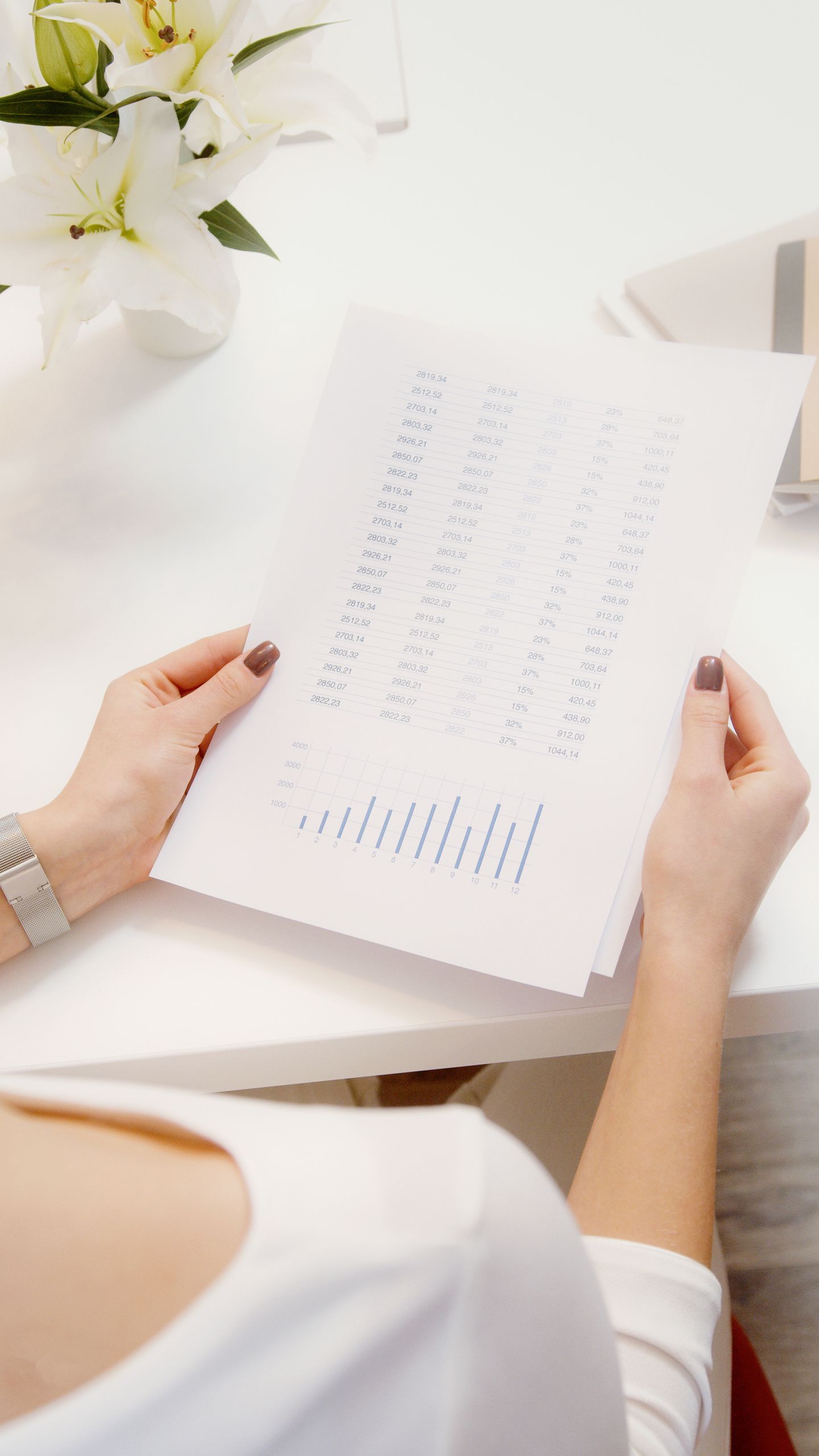 An overhead view of a person reviewing financial documents with graphs.