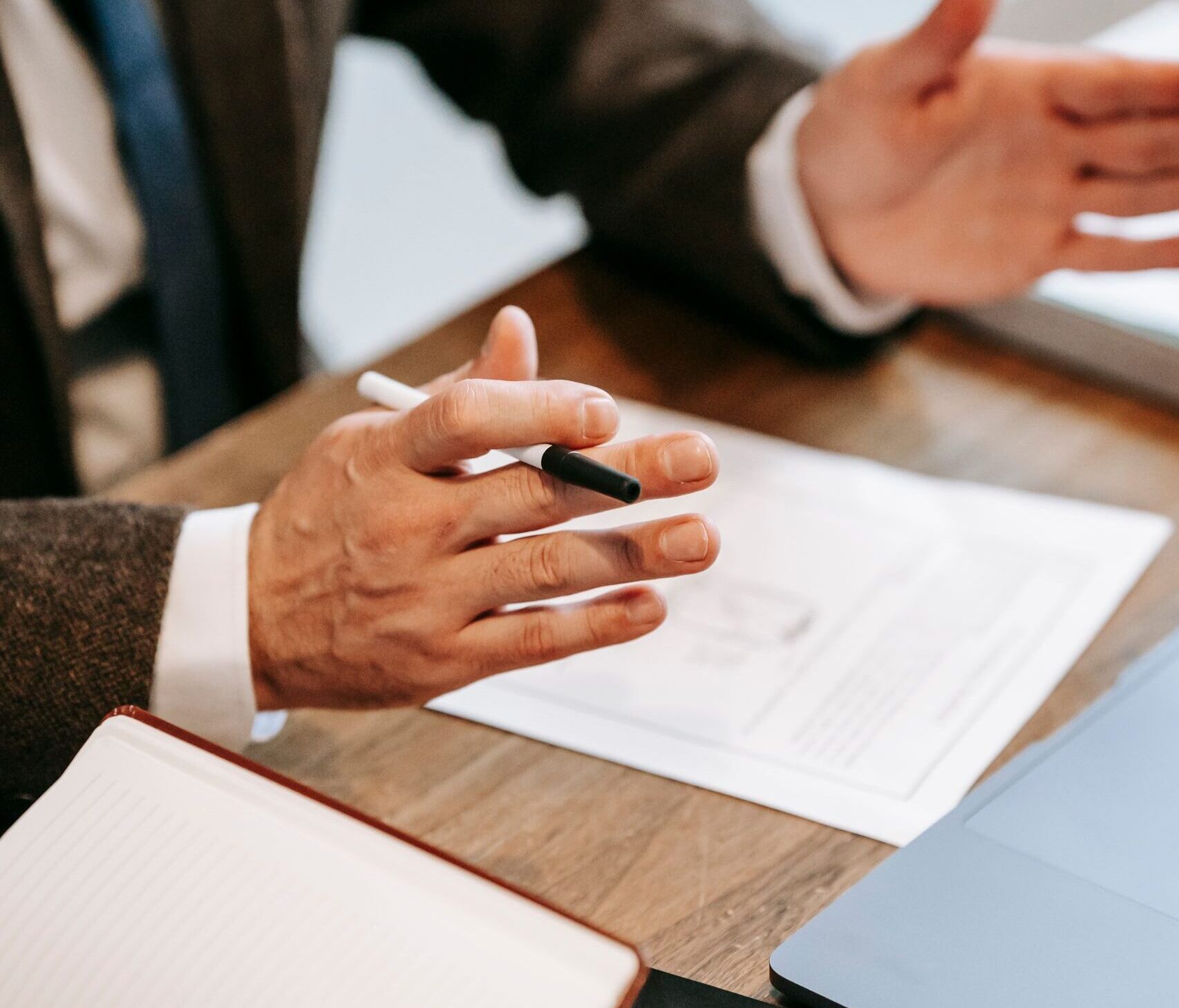 Professional discussing documents over a wooden table in an office setting.