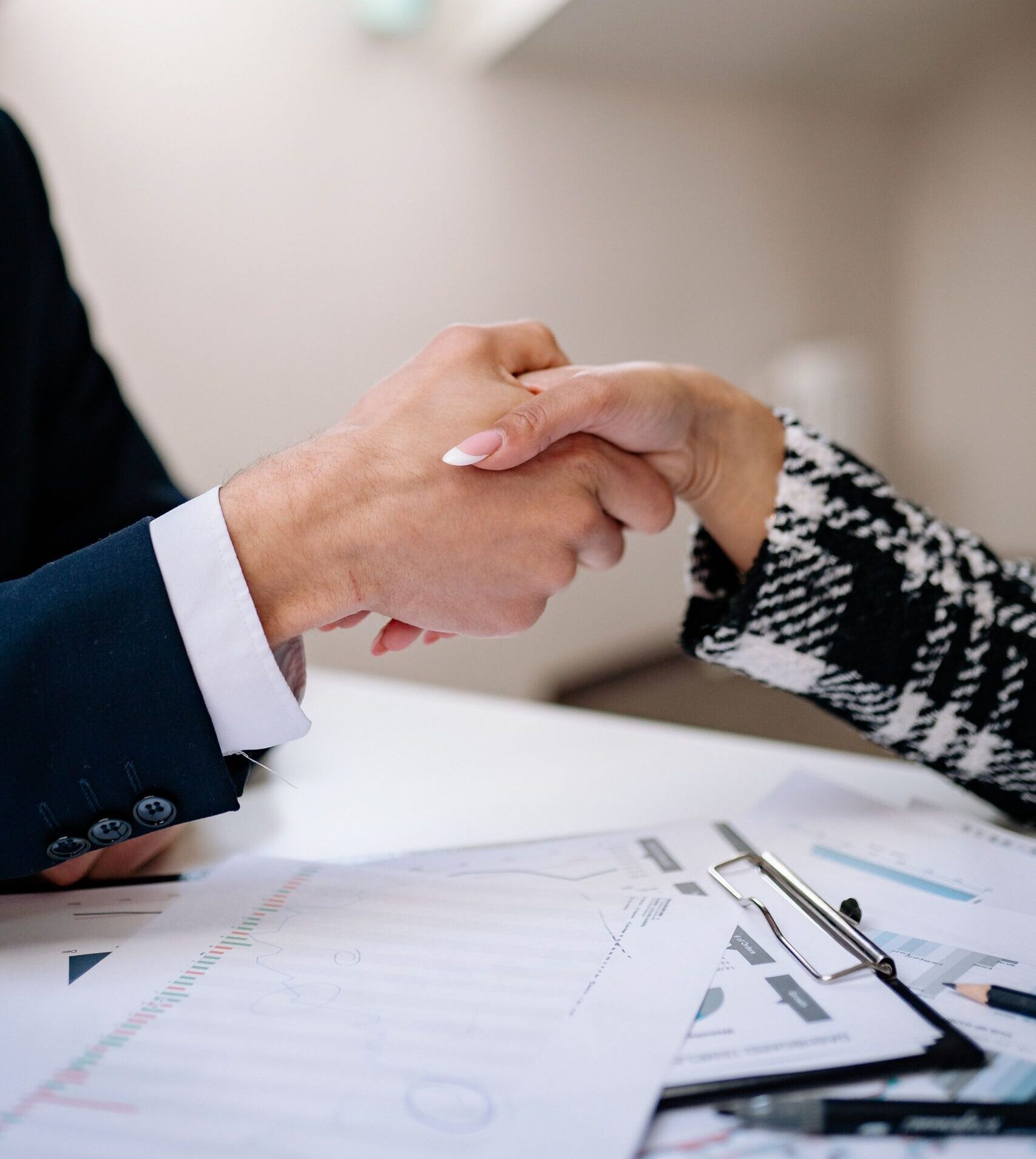 Close-up of a professional handshake between colleagues in a modern office setting, symbolizing agreement.