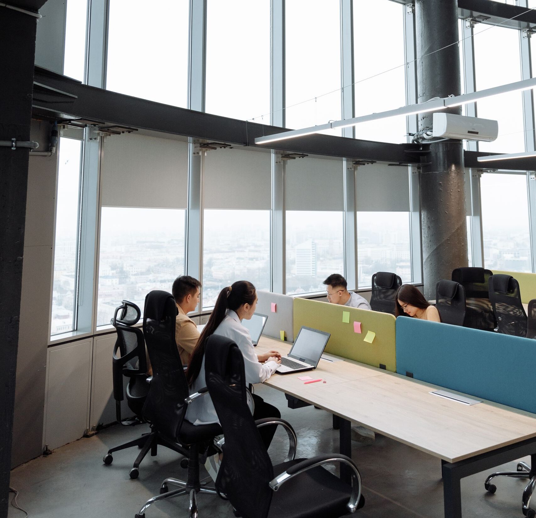 Spacious contemporary office space with employees working on laptops in a high-rise building.